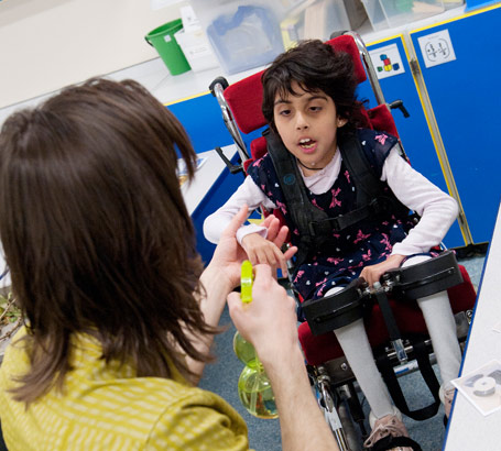 A girl in a specialist chair and
her teacher with a water spray