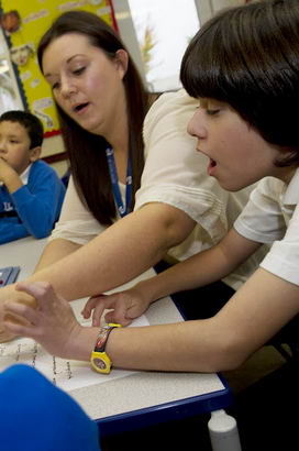 A teacher teaches a young boy
how to write