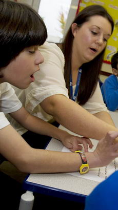 A teacher helps a young boy to
write