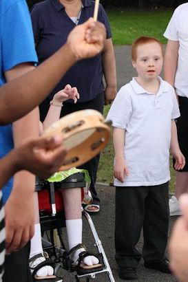 A young boy surrounded by friends, family
and musicians in a playground