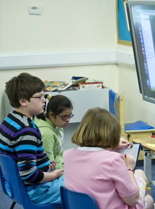 a group of children at various stages
of development sit in a circle with two of their teachers