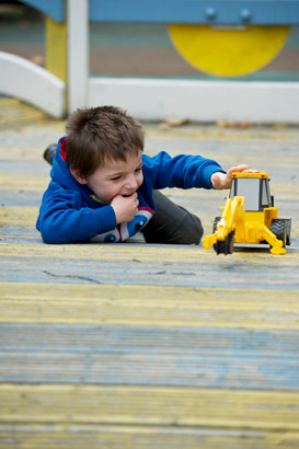 Boy on ground playing with digger
lorry