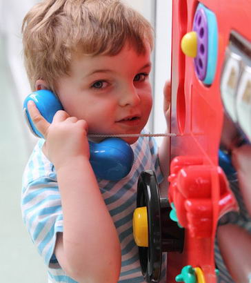 A young boy pretends to speak to someone
using a toy phone