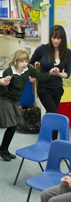 two teachers escort a young girl
back to her chair