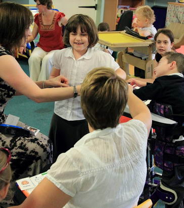 A girl stands, smiling, in a small group
of adults and children