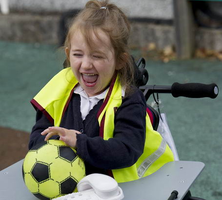 A girl in a playground laughing
with a ball and a telephone