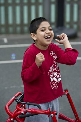 A boy with walking support laughs
in a playground