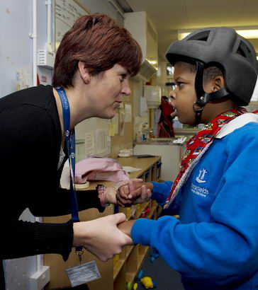 a female teacher holds a male
                  pupil's hand