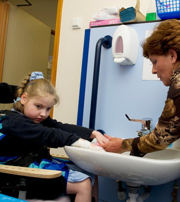 A teacher helps a girl to wash her
hands