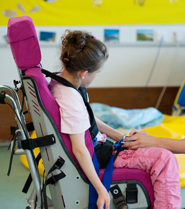 A teacher smiling with a girl in
a specialist chair