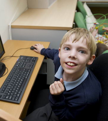 A boy sitting at a computer turns
and smiles