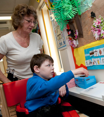 A boy, supervised by a teacher,
reaches towards a wall