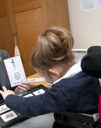 A teacher presents two objects to a girl
wearing head protection