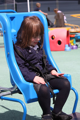 Two girls sit opposite one another in a
                  playground rocking chair