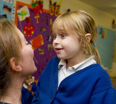 A young girl is lifted up by her
                  female teacher]