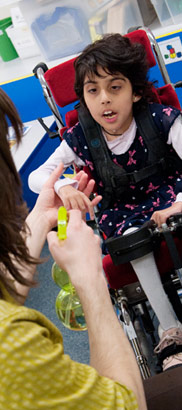 A girl in a specialist chair and
her teacher with a water spray