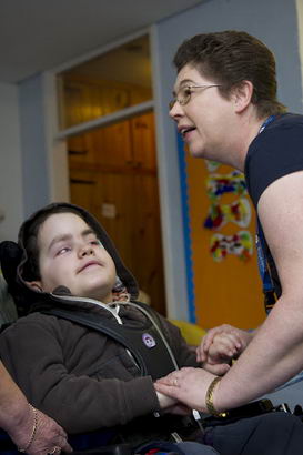 Two nurses comfort a young boy
                  with complex difficulties that have severely affected his development