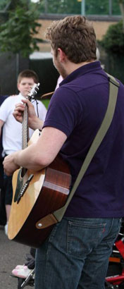 Teacher playing guitar to boy in wheelchair