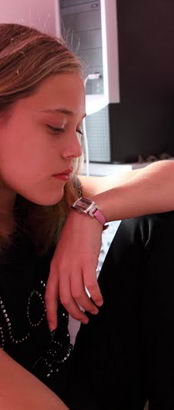 a teenage girl looks pensive as she sits
at the desk in her bedroom