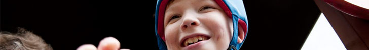 oung boy in protective headgear smiling
                  with teacher/assistant