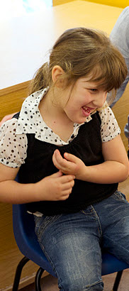 Seated girl laughing with two carers