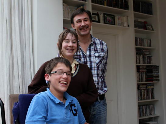Daughter, father and son stand close in their
sitting room