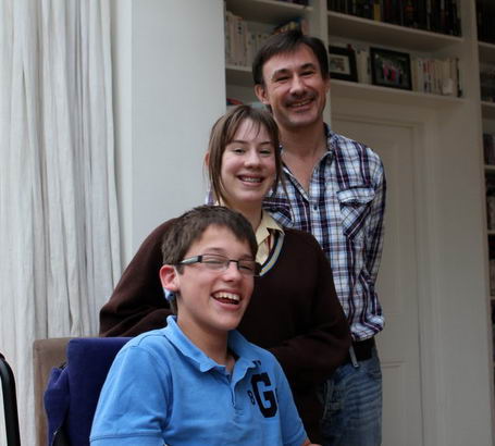 Daughter, father and son stand close in their
sitting room