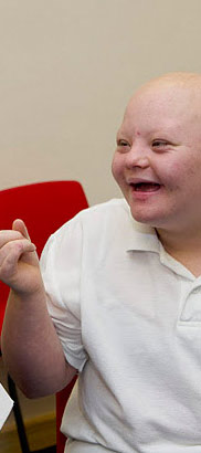 Boy in white shirt laughs with
                  teacher