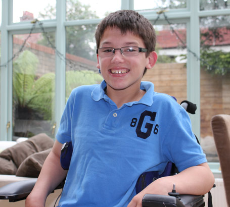 boy in blue shirt in automated wheelchair
smiles at the camera