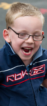 young boy in walking frame moves
from left to right across the frame smiling