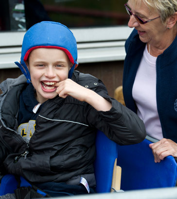 boy with protective helmet laughs
and smiles with his teacher