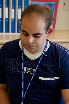 A teacher sits with a boy and
                  helps him to take part in one of his reading interests