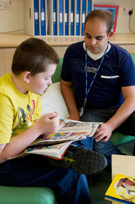 a child sits on a sofa reading
with his caregiver