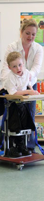 young boy with blue protective headgear
                  smiles at teacher