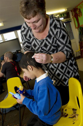 young boy with blue protective headgear
smiles at teacher