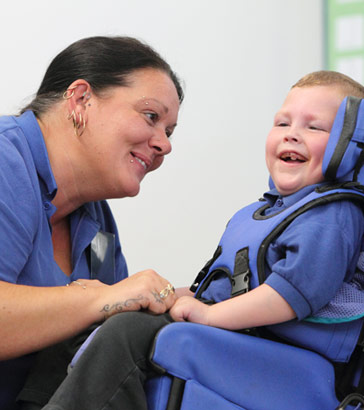 teacher and boy in wheelchair smiling
at each other