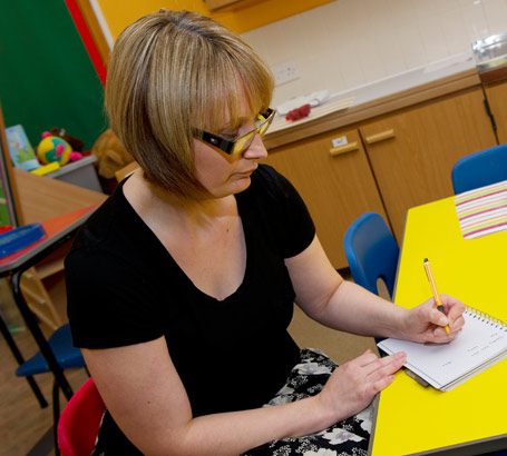 A teacher writes in a small pad
                  of paper