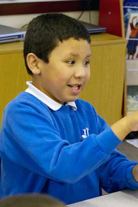 A boy sitting at a table points