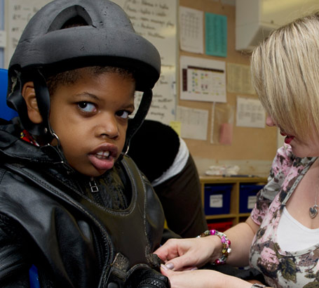 An assistant secures a boy in
a wheelchair