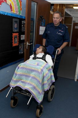 A boy covered in a blanket is
wheeled through a school corridor