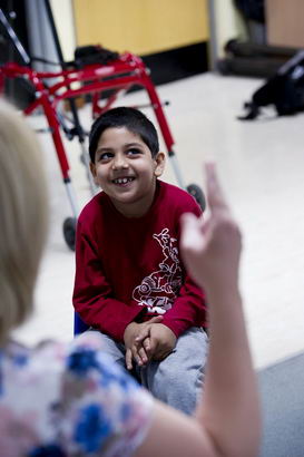 A boy sitting in a chair smiling
                  and looking up