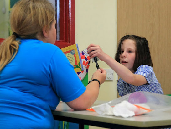 Teacher letting a girl choose between
a book and a comb