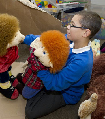 Teacher and child playing with teddy bear