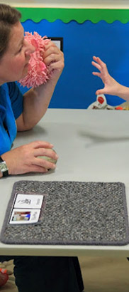 Child reaching for toy in teacher's hand