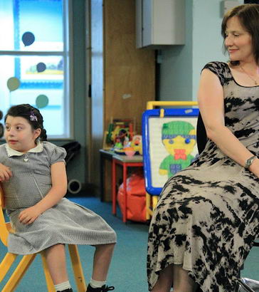 A teacher and a young girl mirror each
                  other's body language whilst sat down