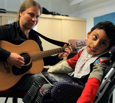 Young boy and teacher interact using guitar
and ipad