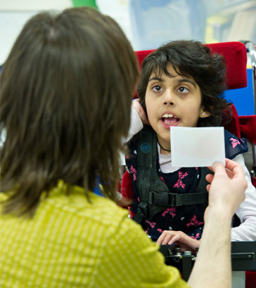 Adult showing a card to a girl in
a wheelchair