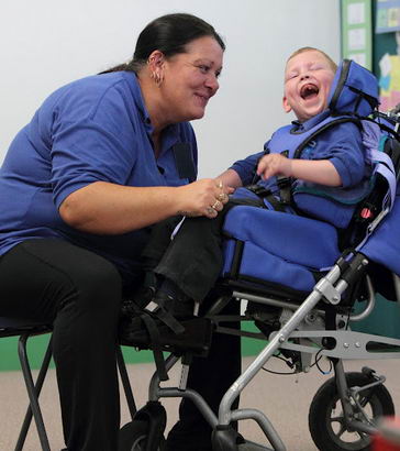 A female teacher and a young boy laugh
and smile