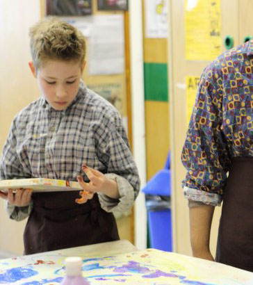 A young boy listens attentively as his
                  teacher plays the guitar