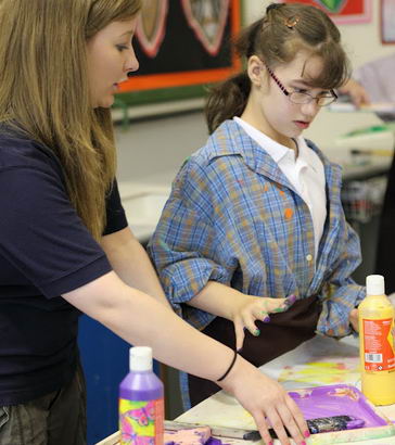 A young girl uses paints